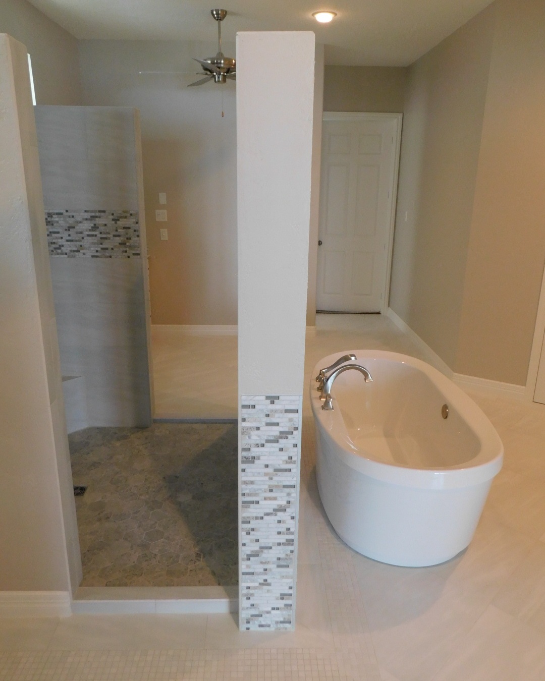 Master Bath Renovation Conroe - Built freestanding wall and tub with deck mounted faucet, decorative back splash tiles and floor border tiles.